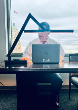 Employee Working in Office With Pure Forms Lamp on Desk
